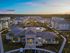 Aerial view of a modern residential community with elegant apartments, lush greenery, and an inviting pool at sunset.