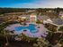 Serene aerial view of a luxury apartment complex pool area with lush greenery and ample seating under soft evening lights.