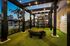 Elegant outdoor gym space with string lights, artificial turf, and modern equipment, overlooking a pool at dusk.
