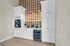 Elegant kitchenette with white cabinetry, coffee machine, and mini-fridge in a modern apartment.