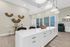Spacious and elegant kitchen with a long white island, modern lighting, and decorative wall accents.