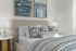 Inviting bedroom featuring a plush beige bed with patterned pillows and stylish wall art above.