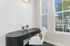 Bright home office nook with a sleek black desk, comfortable white chair, and large windows offering abundant natural light.