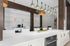 Modern kitchen and dining area with sleek white countertops, stylish pendant lighting, and integrated appliances.