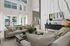 Luxurious living room with modern decor, featuring large windows overlooking a pool area and lush greenery.