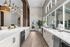 Sleek kitchen interior with long white countertops, modern lighting fixtures, and large windows.