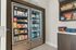 Modern kitchen setup featuring a double-door refrigerator filled with diverse groceries and snacks, alongside sleek shelving.
