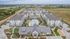 Aerial view of a modern apartment complex with landscaped gardens and a large central swimming pool.