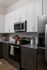 Modern kitchen with sleek white cabinetry, stainless steel appliances, and a granite countertop.