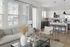 Bright and modern living room with a view of a sleek kitchen featuring contemporary design and large windows.