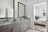 Elegant bathroom with double vanity and a view into a cozy, modern bedroom.