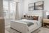 Elegant bedroom with plush bedding, wooden nightstands, and stylish decor in a bright setting.