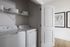 Modern laundry area with a washer and dryer neatly arranged beneath a shelf with stylish baskets.