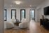 Elegant living room with plush white chairs around a wooden coffee table, bright windows, and decorative accents on wood flooring.