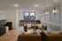 Elegant apartment lounge featuring stylish leather chairs, a wooden herringbone floor, and a bright windowed workspace.