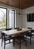 Contemporary dining area with wooden table, plush chairs, and large windows with a garden view.