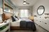 Cozy bedroom with stylish decor, featuring a plush bed, artistic wall decor, and ample natural light.