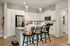 Bright modern kitchen with white cabinetry, stainless steel appliances, and a central island with bar stools.