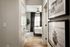 Corridor view leading to a bright bedroom with elegant decor, featuring framed wall art and wooden flooring.