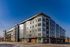 Modern apartment complex with sleek architecture under a clear blue sky, featuring large windows and multiple stories.