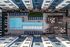 Aerial view of a modern apartment complex featuring a luxurious outdoor swimming pool with stylish loungers, surrounded by beautifully landscaped gardens and a spacious deck area with cozy seating.