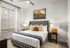 Cozy bedroom featuring stylish plaid headboard, warm lighting, and chic artwork creating a serene ambiance.