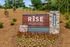 Inviting entrance sign for RISE Red Mountain surrounded by lush landscaping and vibrant flowers.