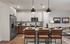 Modern kitchen and living area featuring sleek stainless steel appliances, elegant pendant lighting, and a cozy seating arrangement, creating a welcoming open-concept space perfect for entertaining.