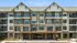 Charming four-story apartment building with stone accents, large windows, and private balconies, set against a clear blue sky.