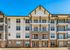 Modern apartment complex with stylish balconies and elegant stonework under a clear blue sky.