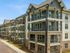 Modern apartment complex featuring elegant stone fa&ccedil;ade, ample balconies, and lush landscaping on a sunny day.