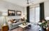 Elegant living room with modern decor, featuring a comfortable gray sofa, stylish pillows, chic lighting, and large windows with blinds.