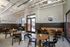 Chic cafe interior with stylish wooden tables, modern black chairs, and motivational 'Dare to Be Bold' wall art, creating an inviting atmosphere.