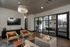 Elegant living area with modern decor, featuring a chic chandelier, plush seating, and a sleek TV setup. Adjacent conference room with large glass doors for a professional touch.