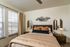Inviting bedroom with cozy bedding, warm lighting, and elegant decor, perfect for relaxation and comfort.