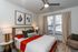 Cozy, modern bedroom with stylish decor, featuring a wooden bed with vibrant bedding, elegant lighting, and artful wall pieces.