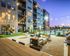 Chic urban apartment exterior with cozy firepit seating, modern landscaping, and ambient string lighting at twilight, perfect for relaxation and social gatherings.