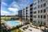 Luxurious apartment complex with modern architecture featuring a sparkling outdoor pool, spacious patio, and scenic park views.