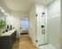 Elegant bathroom with modern fixtures, glass walk-in shower, and double vanity, leading to a cozy bedroom with natural light.