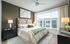 Elegant bedroom with a cozy bed, modern decor, and large windows for natural light. Features calming green walls and stylish lighting.