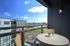 Charming balcony with cozy seating, offering stunning views of the river and city skyline under a clear blue sky.
