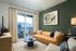 Chic living room with a plush leather sofa, modern art, and a sunlit balcony view.