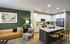 Contemporary open-plan living area featuring a modern kitchen with sleek white cabinets and spacious island, complemented by a stylish lounge with art accents and cozy lighting.