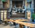 Modern, industrial-style lounge with high ceilings, elegant lighting fixtures, and a sleek wooden table surrounded by stylish chairs, perfect for gatherings.