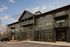 Modern apartment complex with stylish clubhouse and convenient mailroom, featuring balconies and ample parking under a charming sky.