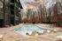 Luxurious outdoor pool area with elegant lounge chairs, surrounded by modern architecture and serene woodlands under a colorful sky.