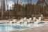 Elegant outdoor swimming pool with modern loungers and natural stone backdrop, surrounded by tranquil wooded scenery.