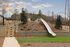 Inviting outdoor playground with a sleek slide, surrounded by beautiful landscaping and a serene sky backdrop.