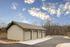 Charming three-door garage with modern design, set against a serene backdrop of lush trees and a clear blue sky.