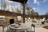 Inviting outdoor space with a fire pit surrounded by Adirondack chairs, two modern grills, and a dining table set with gourmet meals and wine.